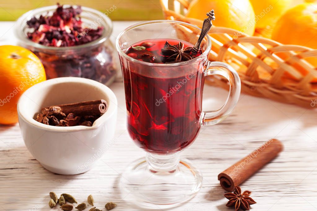 Mulled wine Karkade tea, with a badge and cardamom in a glass on a wooden table top orange