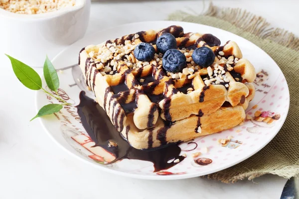 Belgian waffles with peanut chocolate sauce and blueberry, bilberry, whortleberry, huckleberry, hurtleberry, blaeberry on a plate — Stock Photo, Image