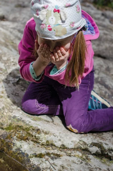 Meisje drinkt uit een bergbeek in het vroege voorjaar — Stockfoto