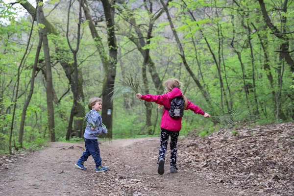 Jongen en meisje spelen als vliegen door het bos in het vroege voorjaar — Stockfoto