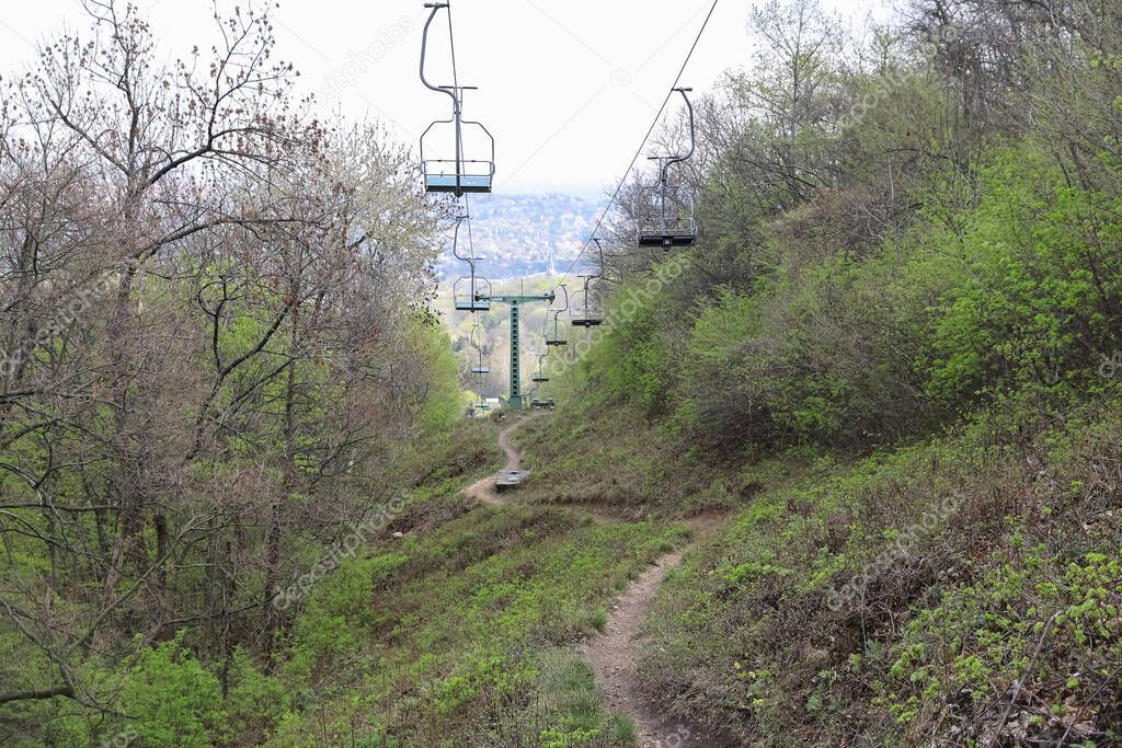 Path under the chairlift in the mountain forest in early spring