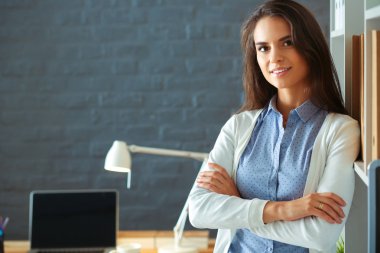 Dizüstü bilgisayarının yanında duran genç bir kadın.