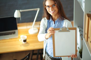 Masanın yanında dizüstü bilgisayarı olan genç bir kadın.