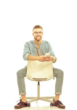 Beyaz arka plan üzerinde izole sandalye üzerinde oturan genç adam