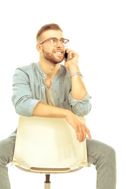 Sandalyede oturan ve cep telefonuyla genç adam