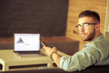 Genç adam kullanarak telefon ve dizüstü bilgisayarda çalışır