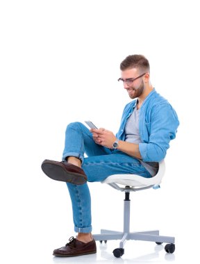 Sandalyede oturan ve cep telefonuyla genç adam