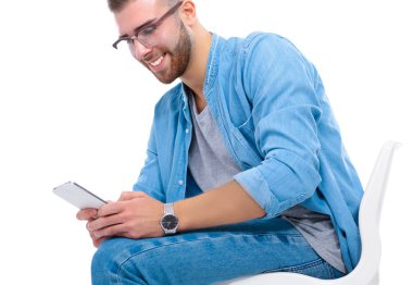 Sandalyede oturan ve cep telefonuyla genç adam