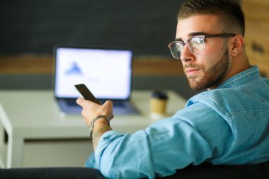 Genç adam kullanarak telefon ve dizüstü bilgisayarda çalışır