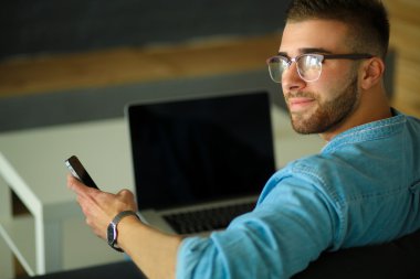 Genç adam kullanarak telefon ve dizüstü bilgisayarda çalışır