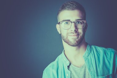 Mutlu bir casual adam ayakta karanlık bir arka plan üzerinde izole portresi