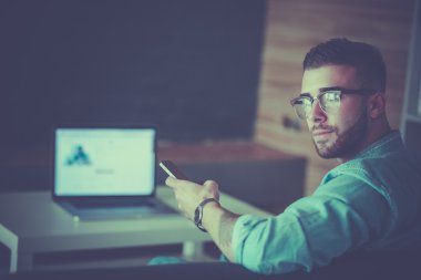Genç adam kullanarak telefon ve dizüstü bilgisayarda çalışır