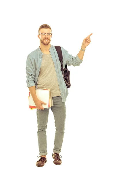 Un estudiante masculino con una bolsa de la escuela sosteniendo libros y señalando aislado sobre fondo blanco —  Fotos de Stock