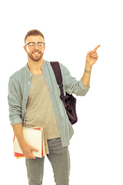 Ученик со школьной сумкой, держащий книги и указывающий на белый фон. — стоковое фото