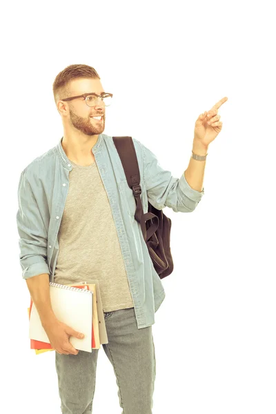 Un estudiante masculino con una bolsa de la escuela sosteniendo libros y señalando aislado sobre fondo blanco —  Fotos de Stock