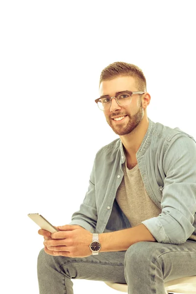 Ung man sitter på stol och med mobiltelefon — Stockfoto