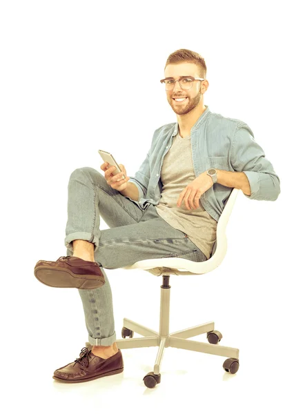 Jonge man zittend op een stoel en gebruik mobiele telefoon — Stockfoto