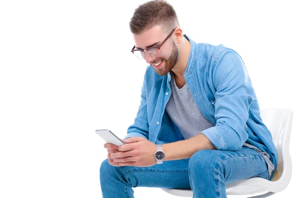 Jeune homme assis sur une chaise et utilisant un téléphone portable — Photo