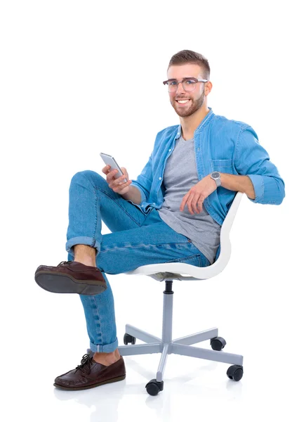 Jeune homme assis sur une chaise et utilisant un téléphone portable — Photo