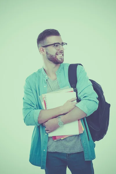 Un estudiante masculino con una bolsa de la escuela sosteniendo libros aislados sobre fondo blanco — Foto de Stock