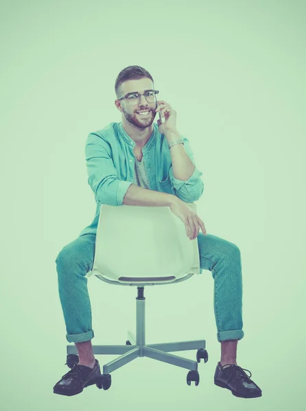 Young man sitting on chair and using mobile phone — Stock Photo, Image