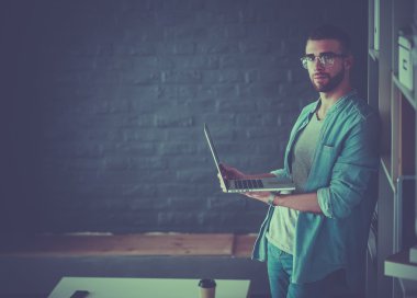 Genç adam dizüstü bilgisayar tutuyor.