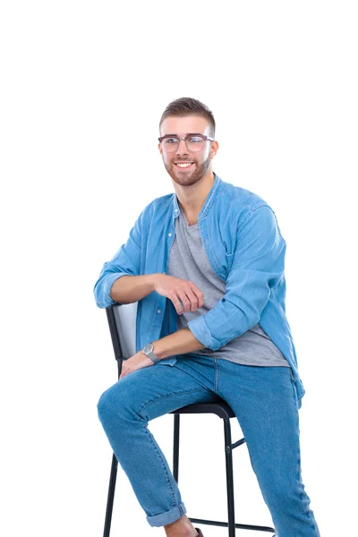 Fiatal ember ül a széken, elszigetelt fehér háttér felett — Stock Fotó