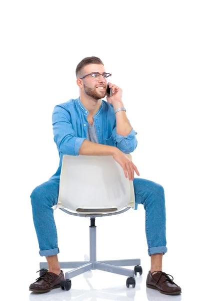 Jonge man zittend op een stoel en gebruik mobiele telefoon — Stockfoto