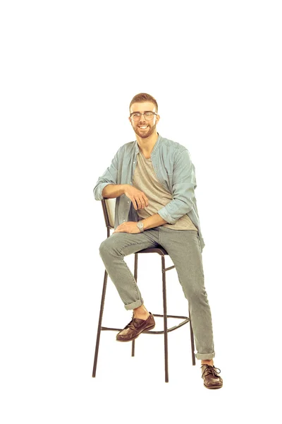 Beyaz arka plan üzerinde izole sandalye üzerinde oturan genç adam — Stok fotoğraf