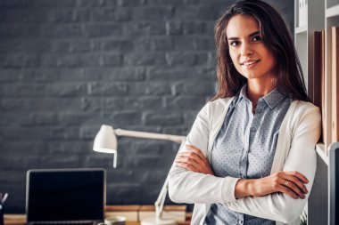 Dizüstü bilgisayarının yanında duran genç bir kadın.