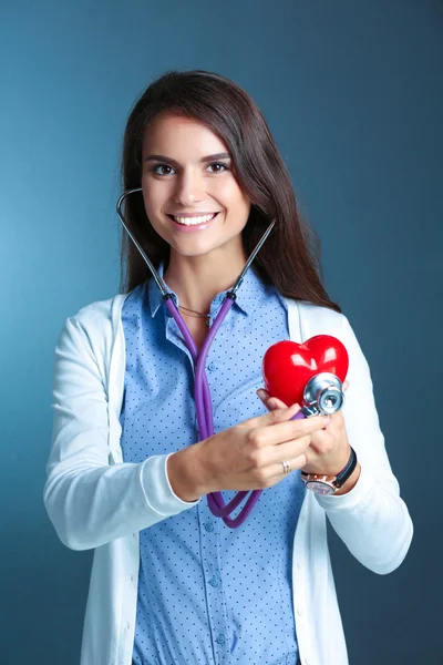 Arzt mit Stethoskop untersucht rotes Herz — Stockfoto
