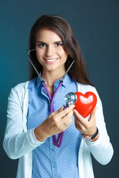Un médecin avec stéthoscope examinant le cœur rouge — Photo