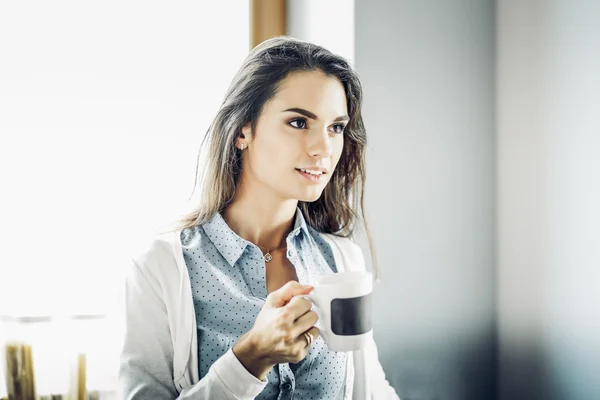 Счастливая женщина пьет чай на кухне дома — стоковое фото