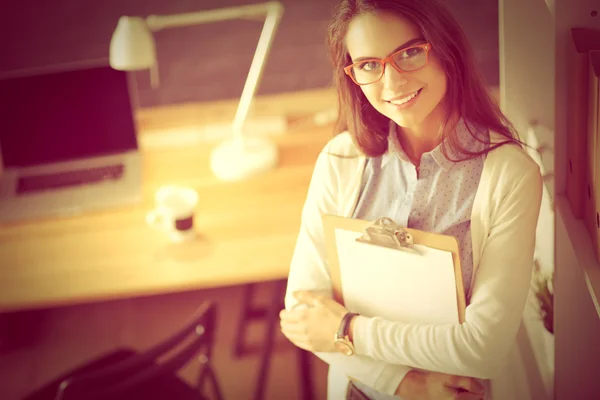 Młoda kobieta stojąca przy biurku z folderem przechowywania laptopa — Zdjęcie stockowe