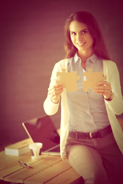 Mujer de negocios sosteniendo y señalando una pieza del rompecabezas —  Fotos de Stock