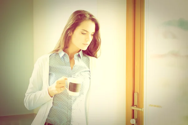 Happy woman drinking tea in the kitchen at home