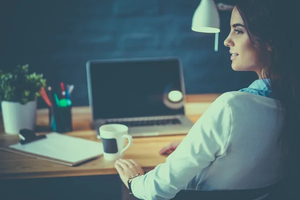 Porträt einer entspannten jungen Frau, die mit einer Tasse Kaffee an ihrem Schreibtisch sitzt — Stockfoto