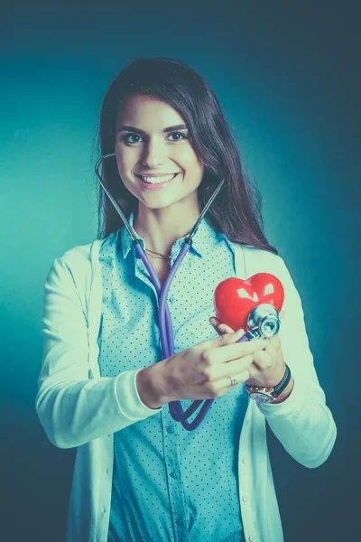 Un médecin avec stéthoscope examinant le cœur rouge — Photo