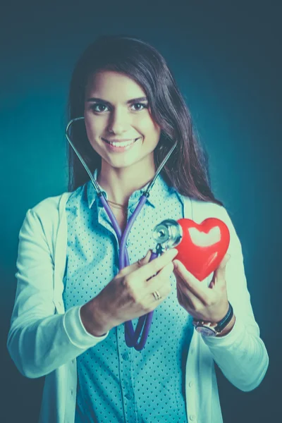 A doctor with stethoscope examining red heart — Stock Photo, Image