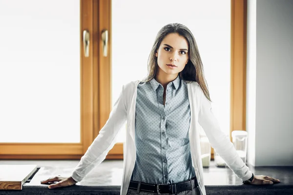 Young woman is standing near window — Stock Photo, Image