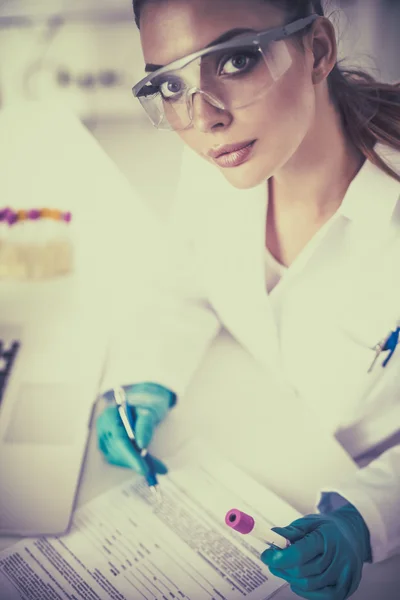 Kobieta badaczka jest otoczona przez fiolki i kolby medyczne, izolowane na białym tle — Zdjęcie stockowe