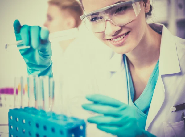 Woman researcher is surrounded by medical vials and flasks, isolated on white background — Stock Photo, Image