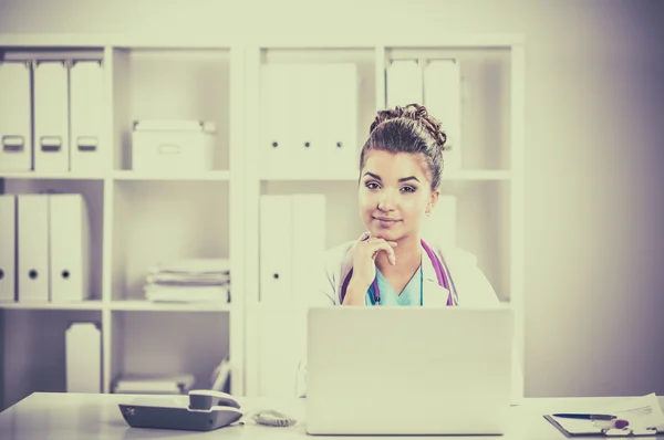 Kadın doktor masada oturuyor ve hastanede dizüstü bilgisayarla çalışıyor. — Stok fotoğraf