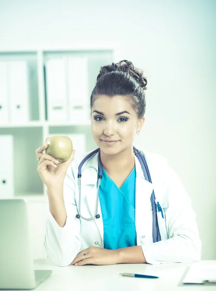 Mujer médico mano sosteniendo una manzana verde, sentado — Foto de Stock