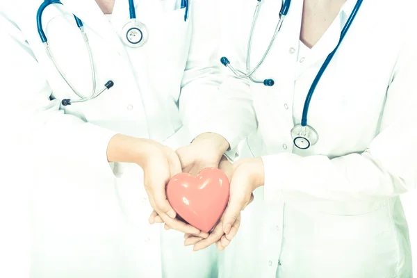 Two woman doctor holding a red heart, isolated on white background — Stock Photo, Image