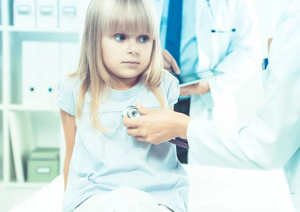 Female doctor examining child with stethoscope at surgery — Stock Photo, Image