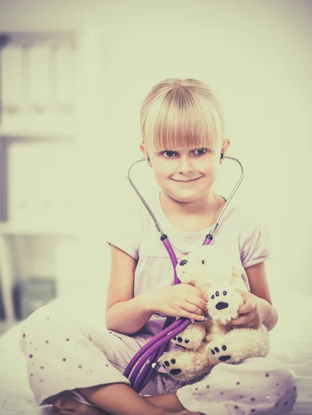 Küçük kız oyuncak ayısını steteskop kullanarak inceliyor. — Stok fotoğraf