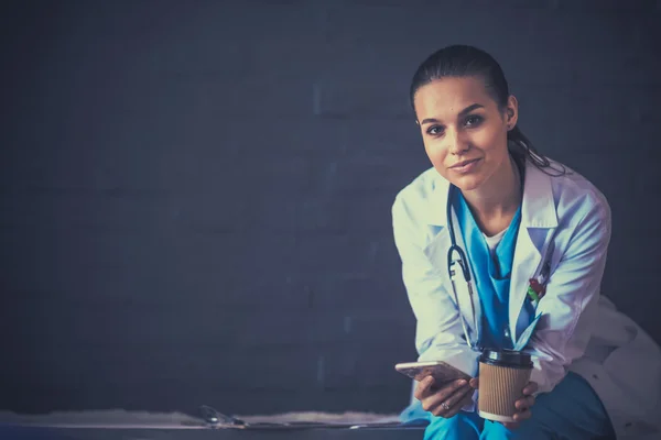 Jonge vrouw arts zitten met uw telefoon — Stockfoto