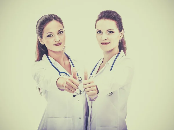 Zwei junge Ärztinnen zeigen Okay, stehen im Krankenhaus — Stockfoto