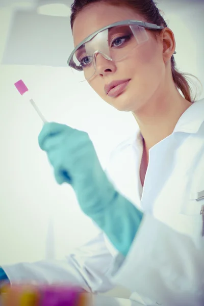 Woman researcher is surrounded by medical vials and flasks, isolated on white background — Stock Photo, Image